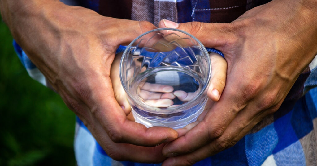 Hands holding a glass of water