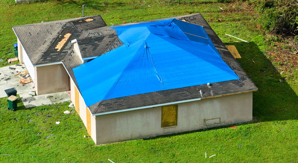 Casa con una lona azul cubriendo el tejado
