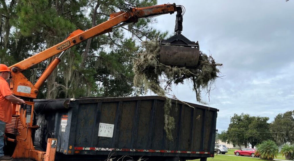 máquina de garras recogiendo escombros del huracán, operario de pie