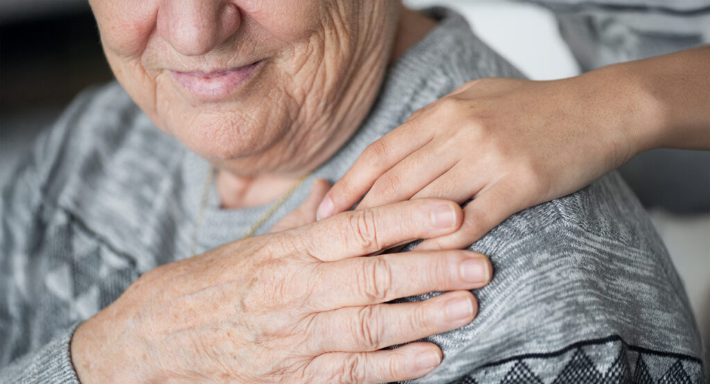 Hand resting on shoulder of elderly person