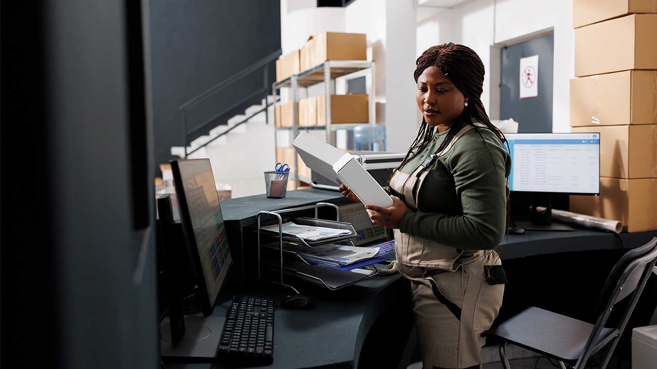 Woman holding files in from of computer