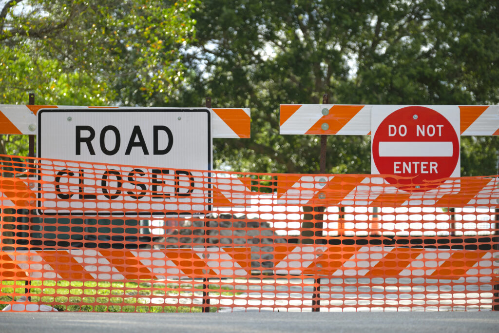 Road closed at construction site with protective fence barrier.