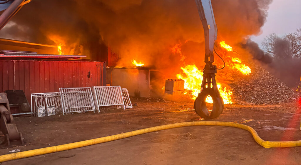 Scrapyard fire in Lakeland, Florida. Claw and fire house in the foreground.