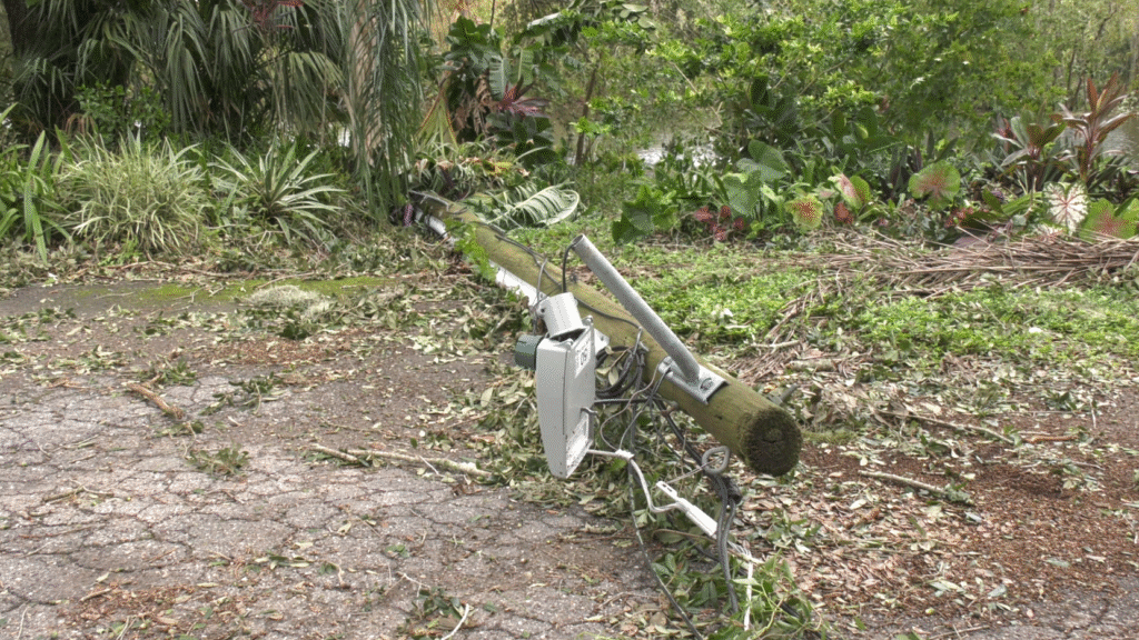 Down power pole and lines laying across a debris filled roadway