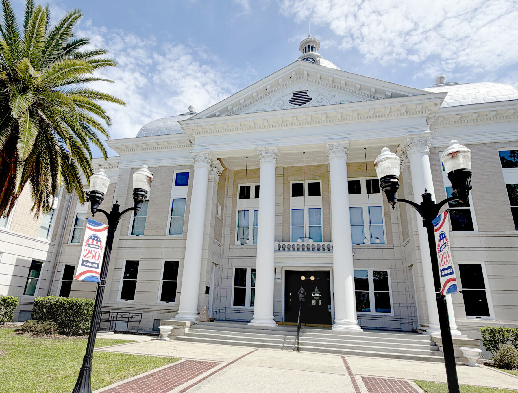 Vista frontal del Centro de Historia del Condado de Polk, un edificio histórico que albergó el juzgado, con columnas blancas, un techo abovedado y una entrada majestuosa.